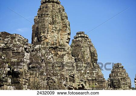 Stock Photo - Massive stone faces in 12th century Bayon Temple which is the central temple in Angkor Thom, located north of Angkor Wat; Siem Reap, Cambodia. Fotosearch