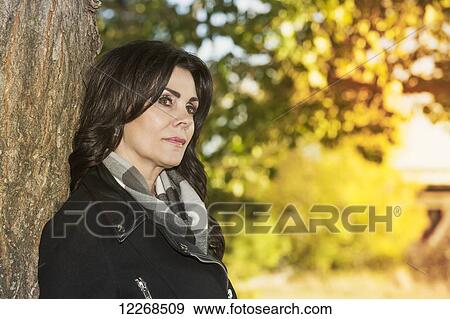 Mature businesswoman standing against a tree in a city park in autumn; Edmonton, Alberta, Canada View Large Photo Image Stock Photo - Mature businesswoman standing against a tree in a city park in autumn; Edmonton, Alberta, Canada. Fotosearch