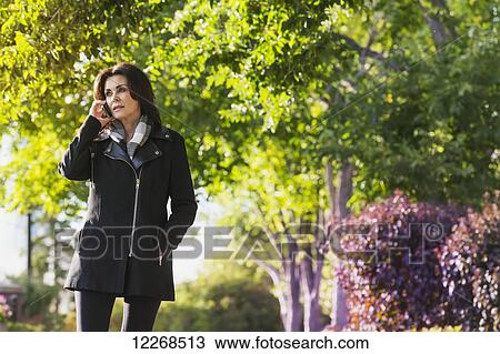 Mature businesswoman talking on her cell phone while walking outdoors in autumn; Edmonton, Alberta, Canada View Large Photo Image Stock Image - Mature businesswoman talking on her cell phone while walking outdoors in autumn; Edmonton, Alberta, Canada. Fotosearch