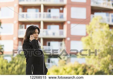 Mature businesswoman talking on her cell phone while walking in an urban park outdoors in autumn; Edmonton, Alberta, Canada View Large Photo Image Stock Photography - Mature businesswoman talking on her cell phone while walking in an urban park outdoors in autumn; Edmonton, Alberta, Canada. Fotosearch