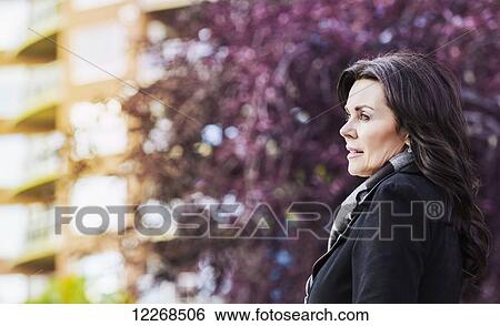 Stock Photograph - Mature businesswoman walking outdoors in a city park in autumn; Edmonton, Alberta, Canada. Fotosearch