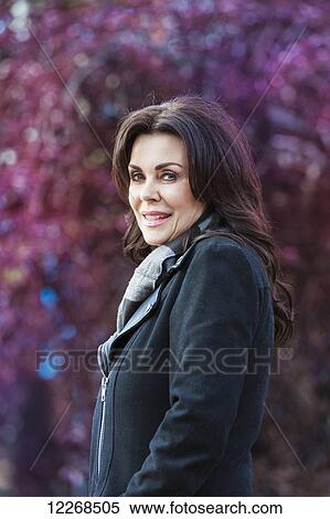 Stock Photography - Mature businesswoman walking outdoors in a city park in autumn; Edmonton, Alberta, Canada. Fotosearch