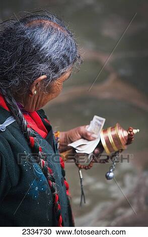 Stock Image - Mature Man Holding Prayer Wheel; Tibet. Fotosearch