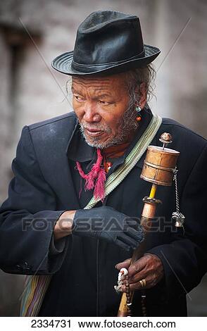 Stock Image - Mature Man Holding Prayer Wheel; Tibet. Fotosearch