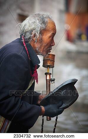 Stock Image - Mature Man Holding Prayer Wheel; Tibet. Fotosearch