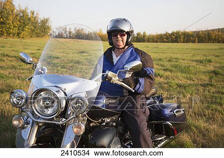 Mature man in field on a motorcycle; Edmonton, Alberta, Canada View Large Photo Image Picture - Mature man in field on a motorcycle; Edmonton, Alberta, Canada. Fotosearch