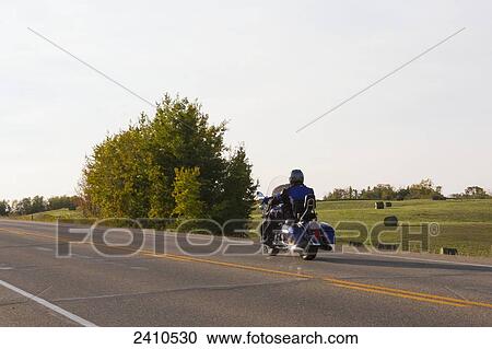 Stock Image - Mature man riding a motorcycle on highway; Edmonton, Alberta, Canada. Fotosearch