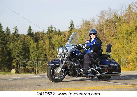 Stock Image - Mature man riding a motorcycle on highway; Edmonton, Alberta, Canada. Fotosearch