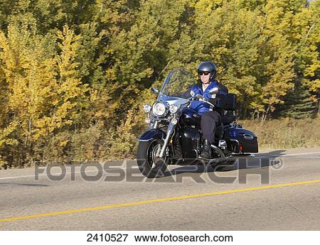 Stock Photo - Mature man riding a motorcycle on highway; Edmonton, Alberta, Canada. Fotosearch