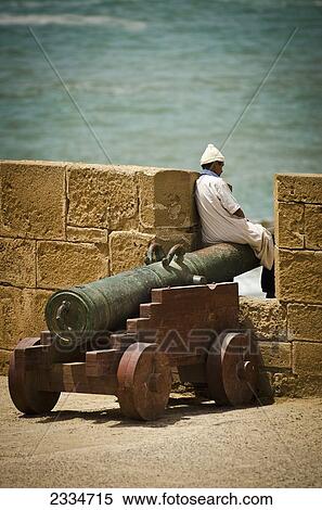 Mature Man Sitting On Cannon; Morocco View Large Photo Image Stock Photography - Mature Man Sitting On Cannon; Morocco. Fotosearch