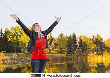 Mature woman with arms raised in worship beside lake in autumn; Edmonton, Alberta, Canada View Large Photo Image Picture - Mature woman with arms raised in worship beside lake in autumn; Edmonton, Alberta, Canada. Fotosearch