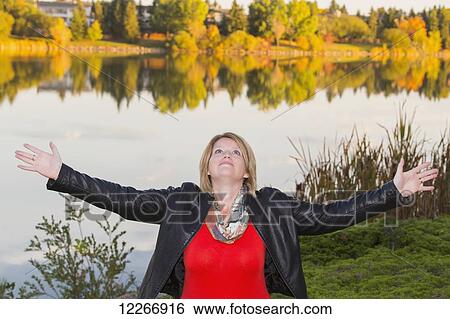 Mature woman with arms raised in worship beside lake in autumn; Edmonton, Alberta, Canada View Large Photo Image Stock Photograph - Mature woman with arms raised in worship beside lake in autumn; Edmonton, Alberta, Canada. Fotosearch