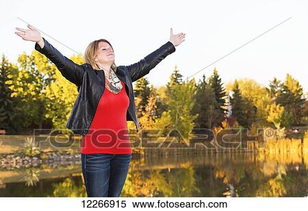 Mature woman with arms raised in worship beside lake in autumn; Edmonton, Alberta, Canada View Large Photo Image Stock Photography - Mature woman with arms raised in worship beside lake in autumn; Edmonton, Alberta, Canada. Fotosearch