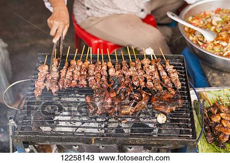 Stock Image - Meat on skewers prepared on the grill in Luh Market; Siem Reap, Cambodia. Fotosearch