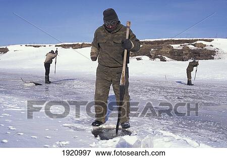 Stock Photo - Men From Sel'kups Tribe Fishing Through Ice On Frozen Lake; Siberia, Russia. Fotosearch
