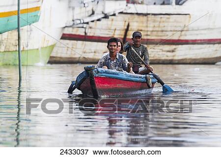 Stock Photo - Men in a boat in Sunda Kelapa Harbour, Jakarta, Java, Indonesia. Fotosearch