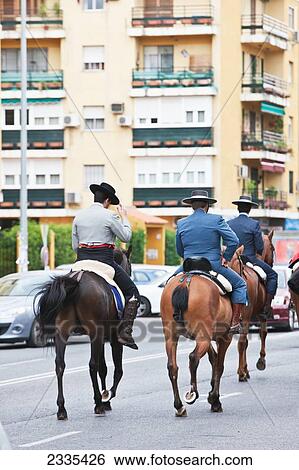 Stock Photograph - Men In Traditional Costume Horseback Riding To April Feria Festival; Seville, Andalucia, Spain, Europe. Fotosearch
