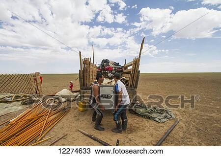 Stock Image - Men loading a safe to a truck, as the nomad family dismantles a Mongolian ger (yurt) to move, Gobi Gurvansaikhan National Park,? mnÃƒÆ’Ã‚Â·govi Province, Mongolia. Fotosearch