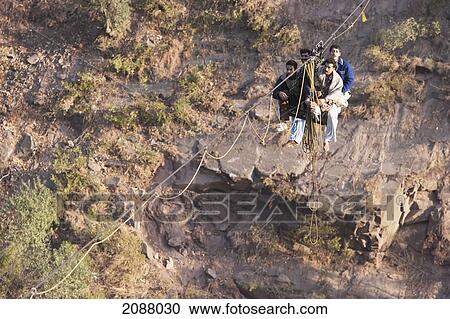 Stock Image - Men On A Ropeway Over The Jhelum River After The 8 October 2005 Earthquake, Azad Kashmir, Pakistan. Fotosearch