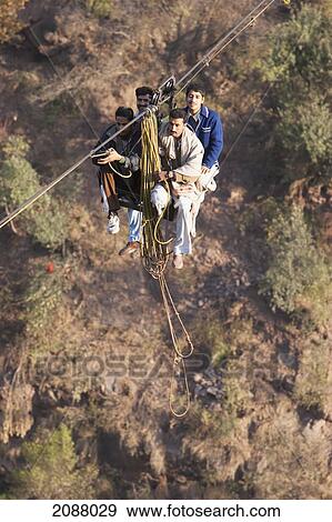 Stock Photo - Men On A Ropeway Over The Jhelum River After The 8 October 2005 Earthquake, Jhelum Valley, Azad Kashmir, Pakistan. Fotosearch