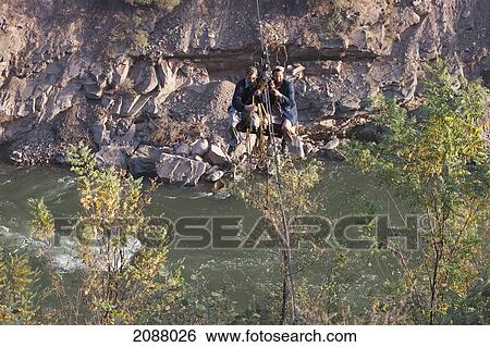 Stock Photograph - Men On A Ropeway Over The Jhelum River After The 8 October 2005 Earthquake, Azad Kashmir, Pakistan. Fotosearch