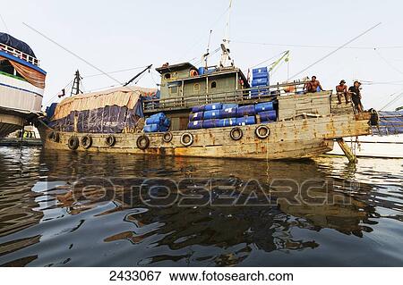 Men on board of a pinisi, a traditional two masted wooden cargo sailing ship moored in Sunda Kelapa Harbour, Jakarta, Java Island, Indonesia View Large Photo Image Stock Photo - Men on board of a pinisi, a traditional two masted wooden cargo sailing ship moored in Sunda Kelapa Harbour, Jakarta, Java Island, Indonesia. Fotosearch