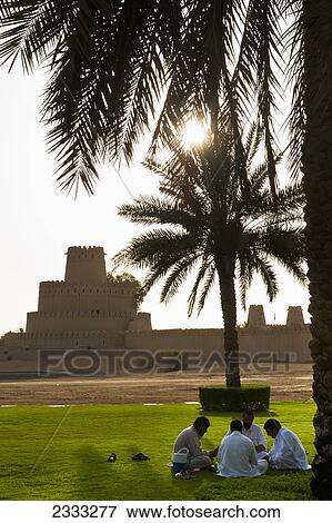 Stock Photo - Men Playing Cards In Front Of Al Jahili Fort; Al Ain, Abu Dhabi, United Arab Emirates. Fotosearch