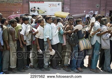 Stock Image - Men queue for free food in Old Delhi. Old Delhi remains the chaotic heart of what is now a sprawling metropolis. Dilapidated and overcrowded its streets are a hive of activity. It was founded by the Mughal Emperor Shahjahan in 1639 and remained the Mug. Fotosearch