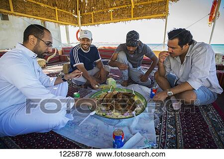 Men sitting and eating goat and rice; Duba, Tabuk, Saudi Arabia View Large Photo Image Stock Photo - Men sitting and eating goat and rice; Duba, Tabuk, Saudi Arabia. Fotosearch