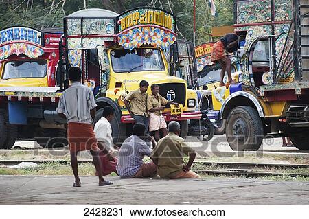Men sitting and standing in the street with colourful trucks; India View Large Photo Image Stock Image - Men sitting and standing in the street with colourful trucks; India. Fotosearch