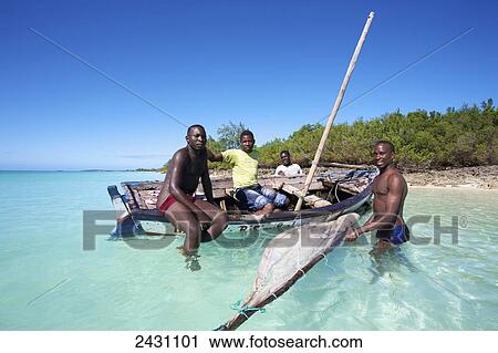 Stock Image - Men sitting in an old wooden sailboat close to the shore; Vamizi Island, Mozambique. Fotosearch