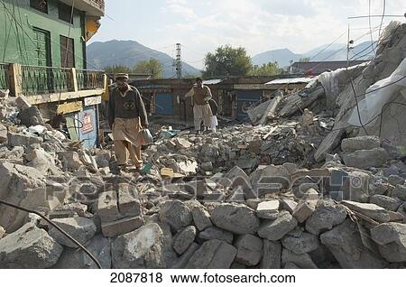 Stock Photo - Men Walking In The Rubble Of A Building Destroyed By The 8 October 2005 Earthquake, Muzaffarabad, Azad Kashmir, Pakistan. Fotosearch