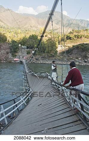 Stock Image - Men Walking On A Collapsed Suspension Bridge Over The Jelhum River After The 8 October 2005 Earthquake, Garhi Dopatta, Azad Jammu & Kashmir, Pakistan. Fotosearch