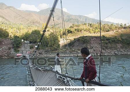Stock Image - Men Walking On A Collapsed Suspension Bridge Over The Jelhum River After The 8 October 2005 Earthquake, Garhi Dopatta, Azad Jammu & Kashmir, Pakistan. Fotosearch