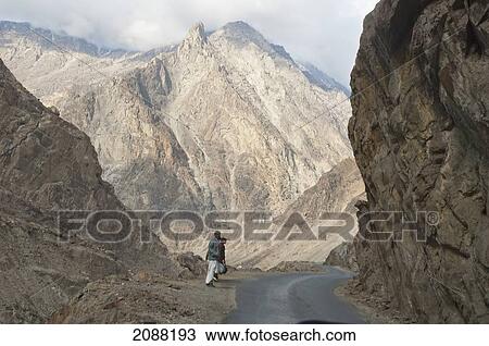 Stock Image - Men Walking On Highway S1 (Gilgit To Skardu) By The Indus River Gorge, Skardu, Northern Areas, Pakistan. Fotosearch