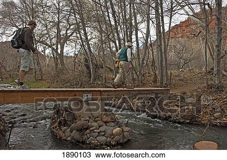 Stock Image - Men Walking Over A Stream While Out On A Nature Walk At Red Rock State Park.. Fotosearch