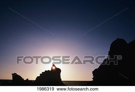 Mexico, Cabo San Lucas At Sunset, Sunlight Shining Through Rocky Formation On Beach. View Large Photo Image Stock Photo - Mexico, Cabo San Lucas At Sunset, Sunlight Shining Through Rocky Formation On Beach.. Fotosearch