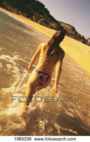 Stock Photograph - Mexico, Cabo San Lucas, View From Behind Of Woman Walking Out Of Ocean Water On Beach.. Fotosearch