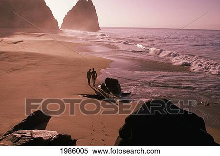 Mexico, Couple walking along misty beach at sunset; Cabo San Lucas View Large Photo Image Stock Photography - Mexico, Couple walking along misty beach at sunset; Cabo San Lucas. Fotosearch