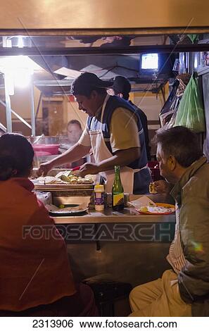 Stock Photograph - Mexico, Guanajuato, San Luis de la Paz, Customers eating at street side taco stand. Fotosearch