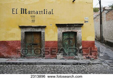 Stock Photograph - Mexico, Guanajuato, San Miguel de Allende, Front view of building with yellow paint and two wooden gates. Fotosearch