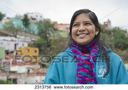 Stock Photograph - Mexico, Guanajuato State, Guanajuato, Portrait of girl with old Mexican homes on hillside in background. Fotosearch