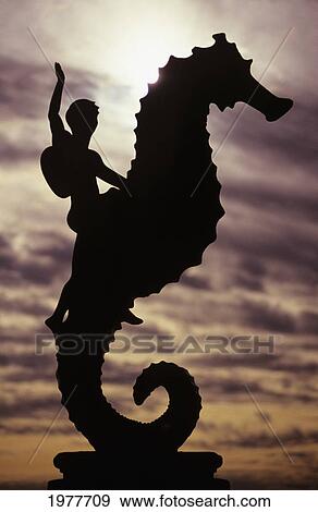 Stock Photo - Mexico, Puerto Vallarta, Boy Silhouette On Large Seahorse Statue.. Fotosearch