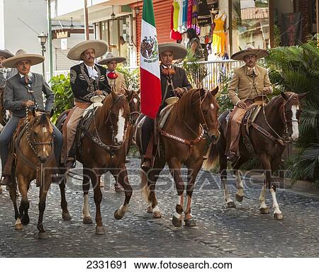 Stock Image - Mexico, specific type of Mexican rodeo here in parade; Puerto Vallarta, The traditional Mexican charro is known for colorful clothing and participating in coleadero y charreada. Fotosearch