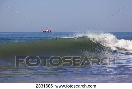 Stock Photograph - Mexico, Wave crashing close to shore with ship in distance; Puerto Vallarta. Fotosearch