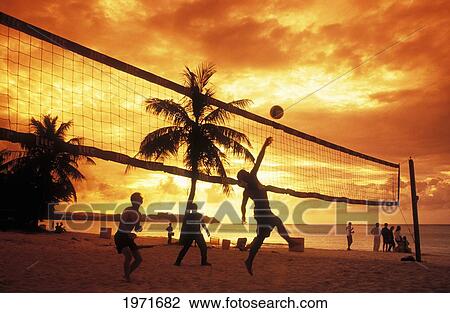 Stock Image - Micronesia, Guam, Tumon Bay, People Playing Volleyball On Beach At Sunset.. Fotosearch
