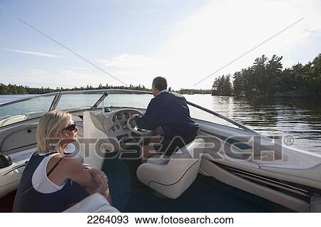 Stock Image - Middle-Aged Couple Travelling By Motorboat In The Lake Of The Woods; Kenora Ontario Canada. Fotosearch