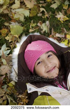 Stock Photography - Middle Eastern Girl Lying In Autumn Leaves Outside Esl School; Guelph Ontario Canada. Fotosearch