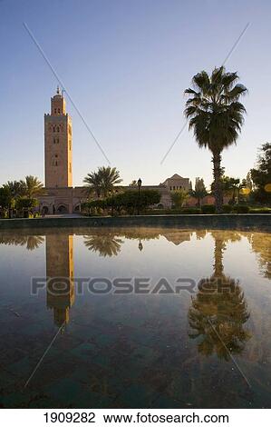 Stock Image - Minaret Of Koutoubia Mosque And Palm Tree Reflected In Fountain At Dawn, Marrakesh, Morocco. Fotosearch
