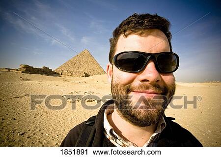 Stock Image - Mna Standing In Desert With Pyramid In Background. Fotosearch
